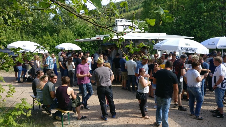 Grill mit Fleisch und Menschen bei einem Dorffest